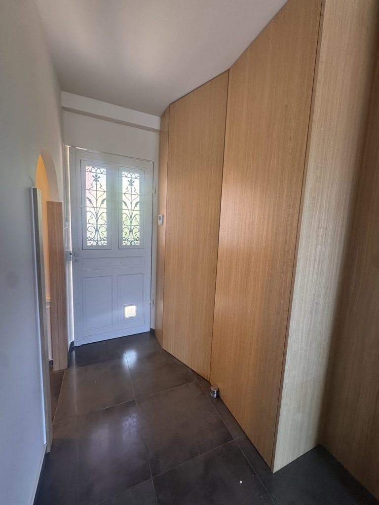 Meuble d'entrée sur mesure en bois suivant la courbe du mur, tableau électrique dissimulé