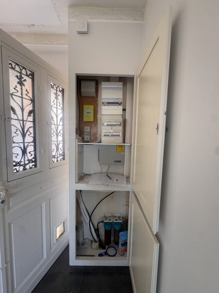 Tableau électrique apparent dans l'entrée avant la création du meuble sur mesure
