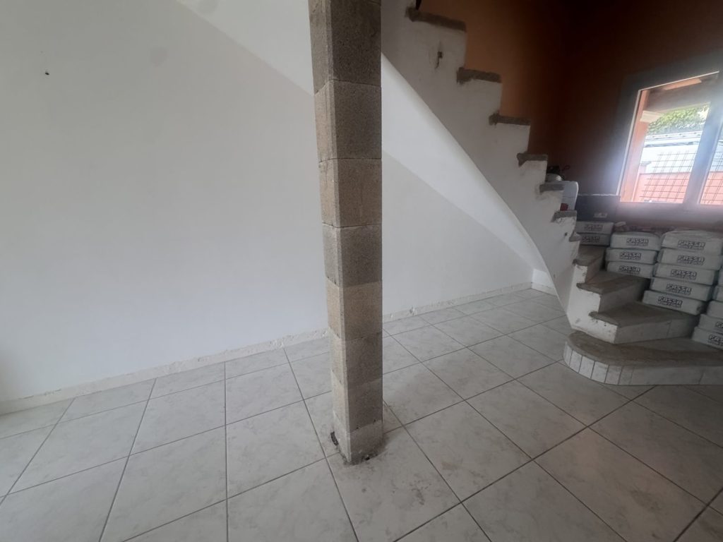 Espace sous l'escalier inexploité avant travaux, avec pilier apparent