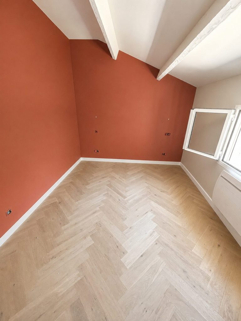 Parquet contrecollé posé en chevron, chambre lumineuse aux murs terracotta